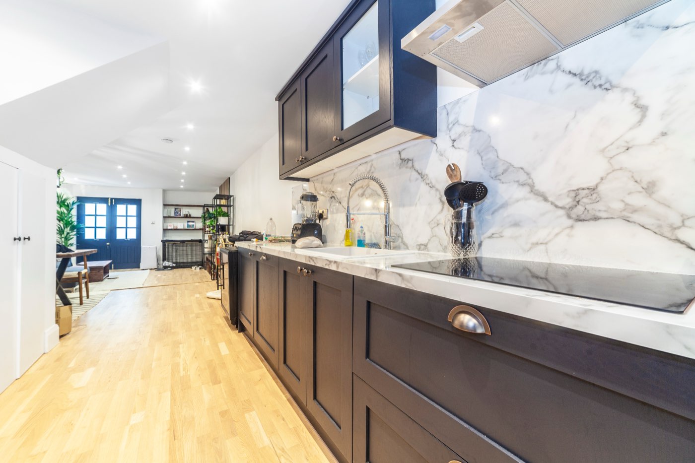 Kitchen with a marble splashback and dark cabinetry in the Wheler Street renovation by LINX
