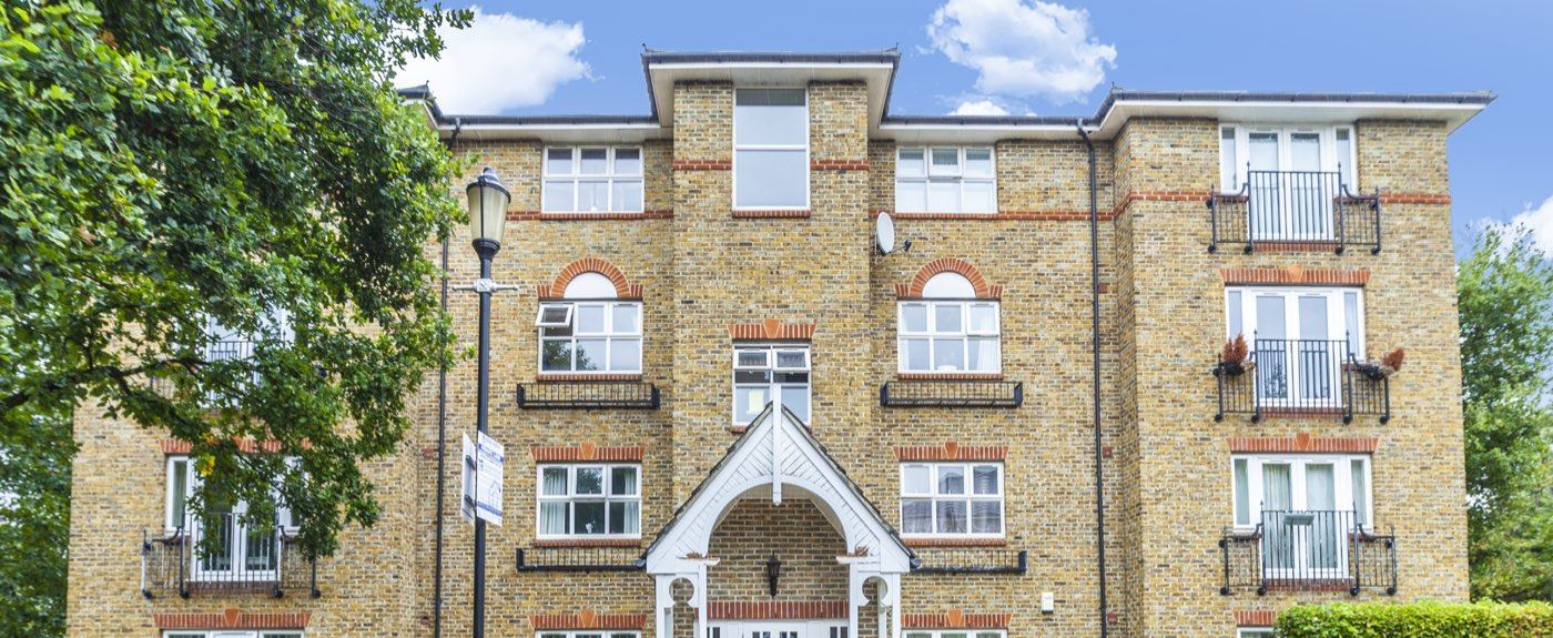 Four-storey brick residential block with a white timber entrance porch and Juliet balconies
