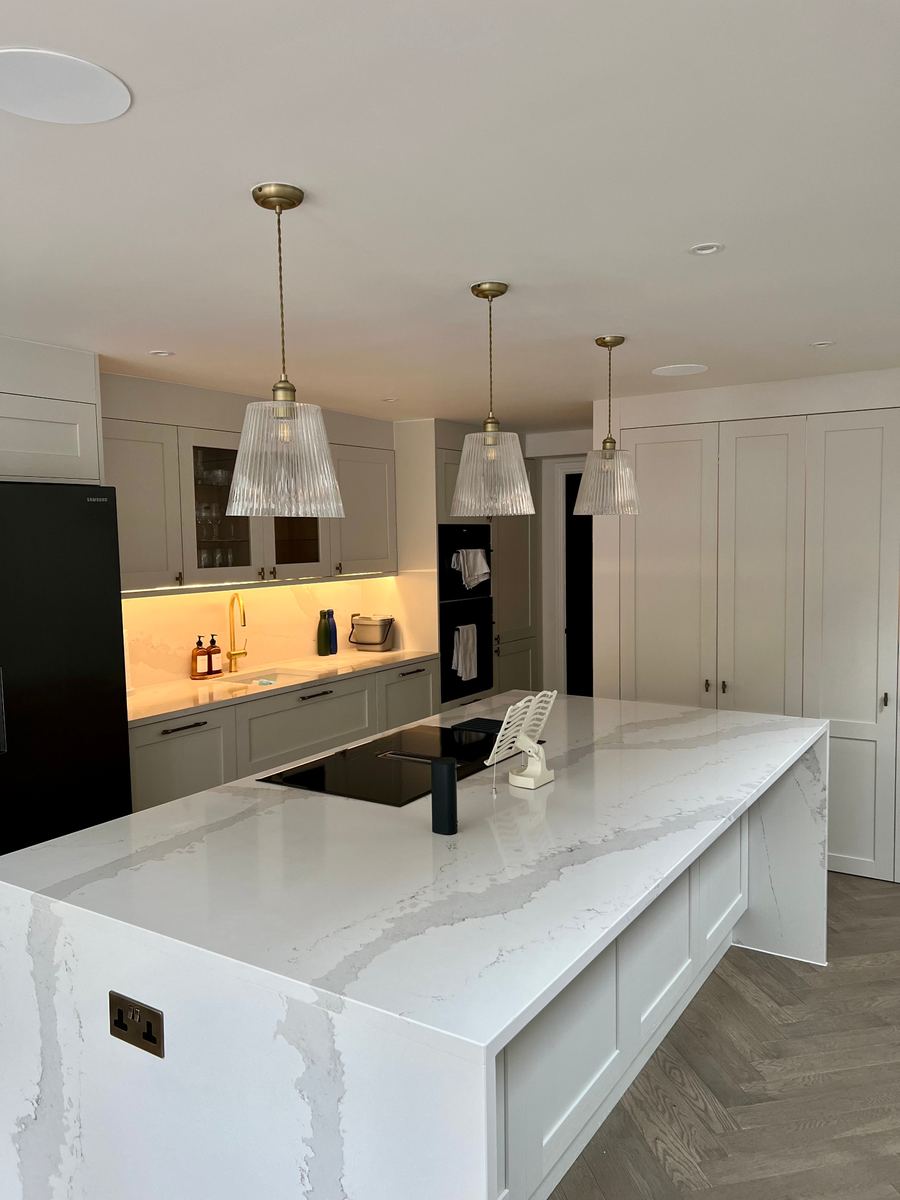 Kitchen island with a marble-effect worktop under three glass pendant lights in a LINX project
