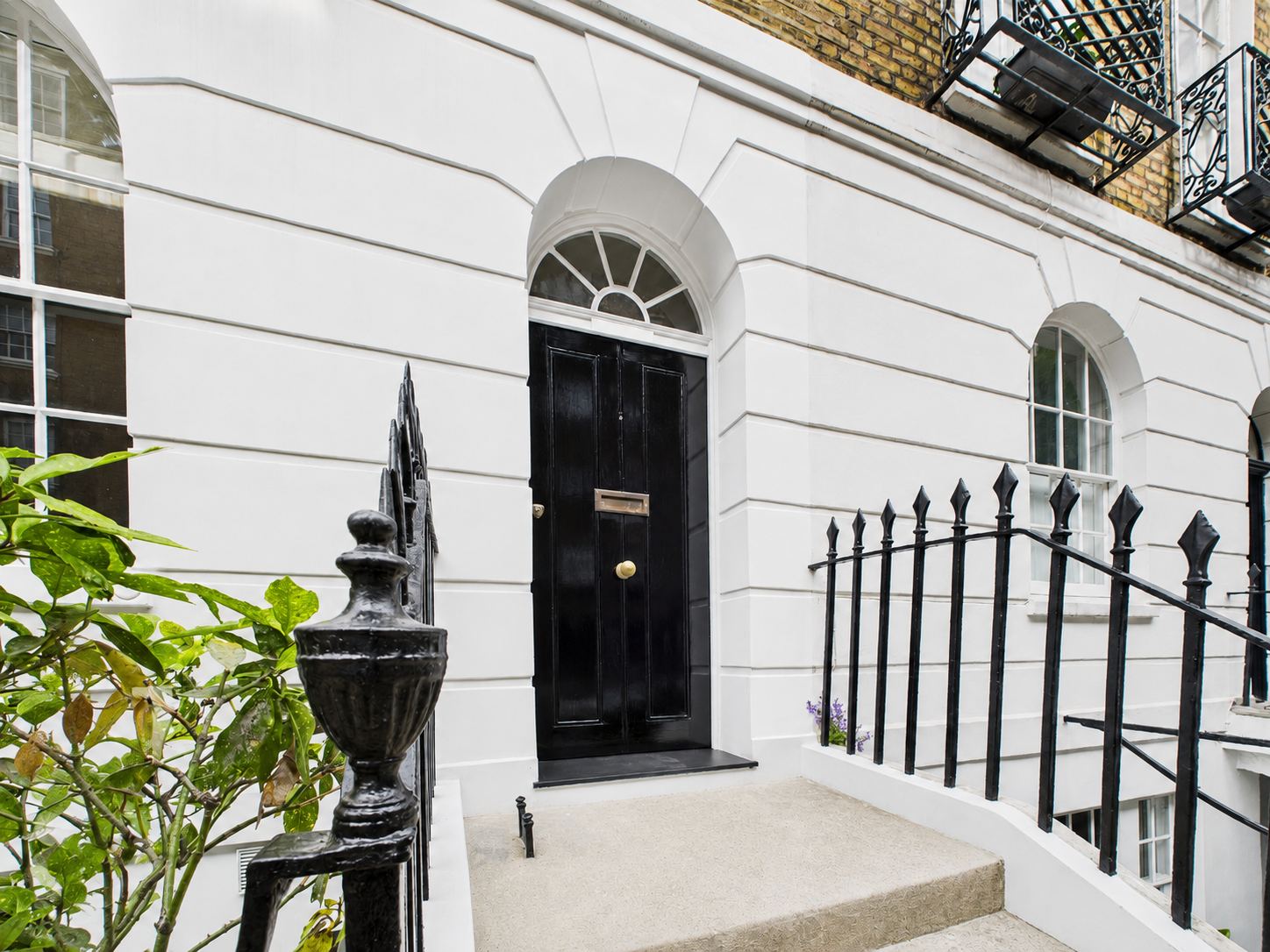 LINX design visual: the entrance of a white stucco townhouse with black railings