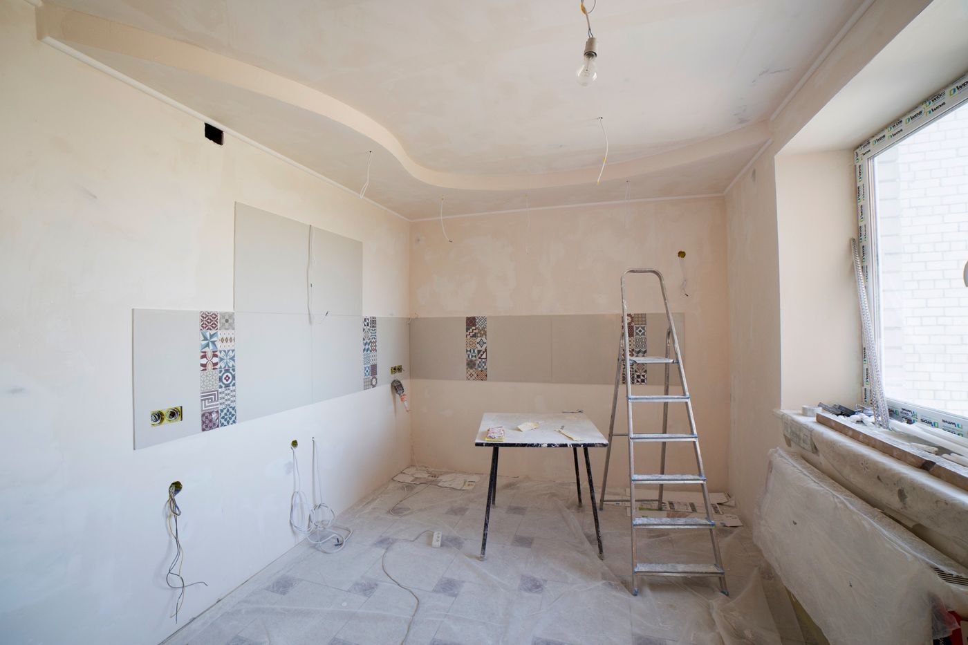 Room stripped back to bare walls and ceiling, with a stepladder and trestle table